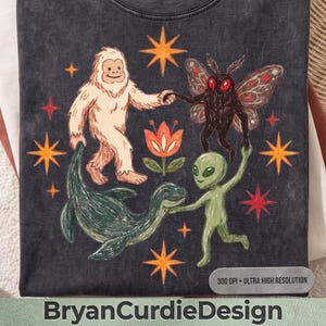 Può includere: Una t-shirt grigio antracite con un'illustrazione grafica di un Bigfoot bianco, una creatura nera simile a una falena, un mostro marino verde e un alieno verde che si tengono per mano attorno a un fiore arancione centrale.