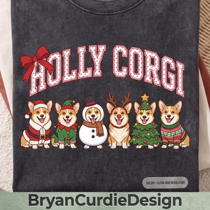 Peut inclure: Un t-shirt gris anthracite avec le texte HOLLY CORGI en blanc à contours rouges et un nœud rouge. En dessous, six chiens Corgi sont illustrés portant des costumes de fête : un costume de Père Noël, une tenue d'elfe, un costume de bonhomme de neige, des bois de renne, un sapin de Noël et un pull à motifs.