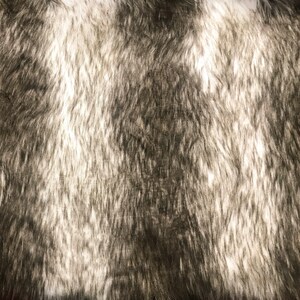 May include: Close-up of a soft, plush fabric with a black and white fur pattern. The fabric has a fuzzy texture and a subtle sheen.