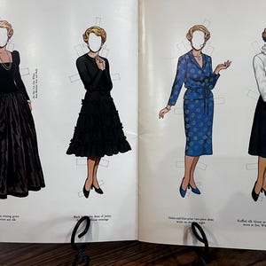 May include: Vintage paper dolls featuring four different outfits. The outfits include a black evening gown, a black dress with a tiered skirt, a blue two-piece dress with a floral pattern, and a white blouse with a black A-line skirt.