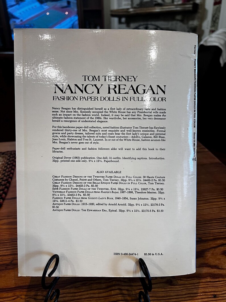 May include: A book titled "Nancy Reagan Fashion Paper Dolls in Full Color" by Tom Tierney. The cover features text and is a paperback. The book is a Dover publication from 1983.