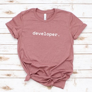 Peut inclure: Un t-shirt mauve avec le texte "developer." imprim&eacute; en blanc sur le devant.
