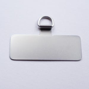 May include: A silver rectangular tag with a silver ring attached to the top. The tag is blank and ready to be personalized.