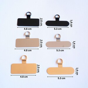 May include: Three sets of metal picture hangers with a loop at the top. Each set includes a black, silver, and gold hanger. The hangers are 4.8 cm wide and 5.3 cm long.