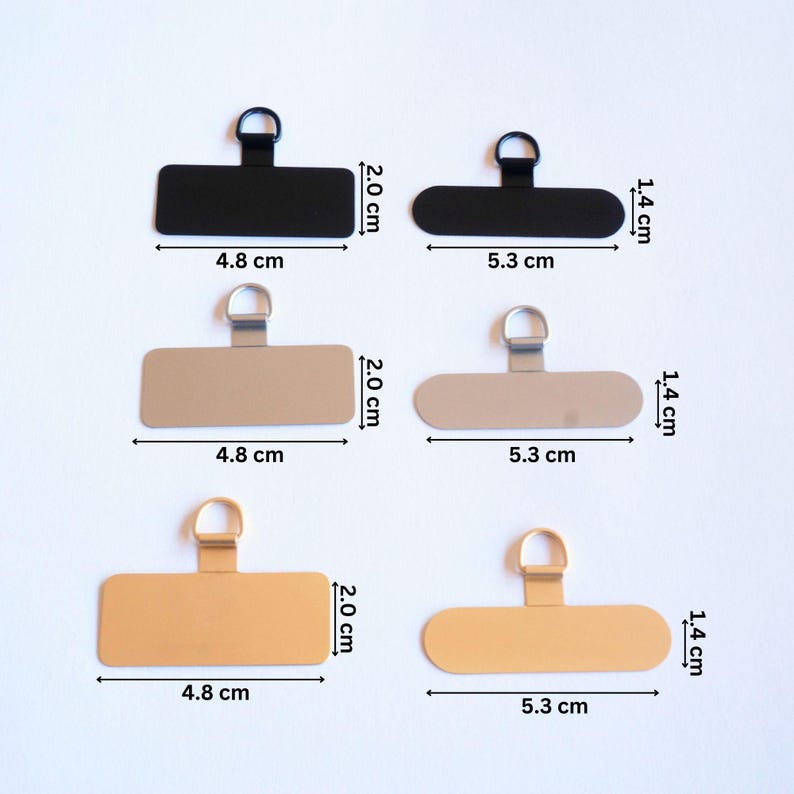 May include: Three sets of metal picture hangers with a loop at the top. Each set includes a black, silver, and gold hanger. The hangers are 4.8 cm wide and 5.3 cm long.