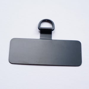 May include: A black metal tag with a rounded rectangular shape and a metal ring at the top.
