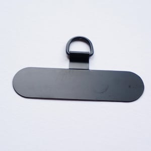 May include: Black metal hanging hardware with a D-ring and a flat rectangular plate.