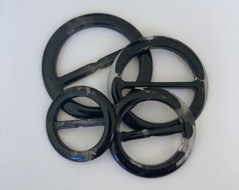 May include: Four black and white marbled plastic belt buckles of different sizes.