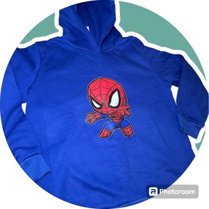 May include: A blue hooded sweatshirt featuring a cartoon image of Spiderman in a red and blue suit.