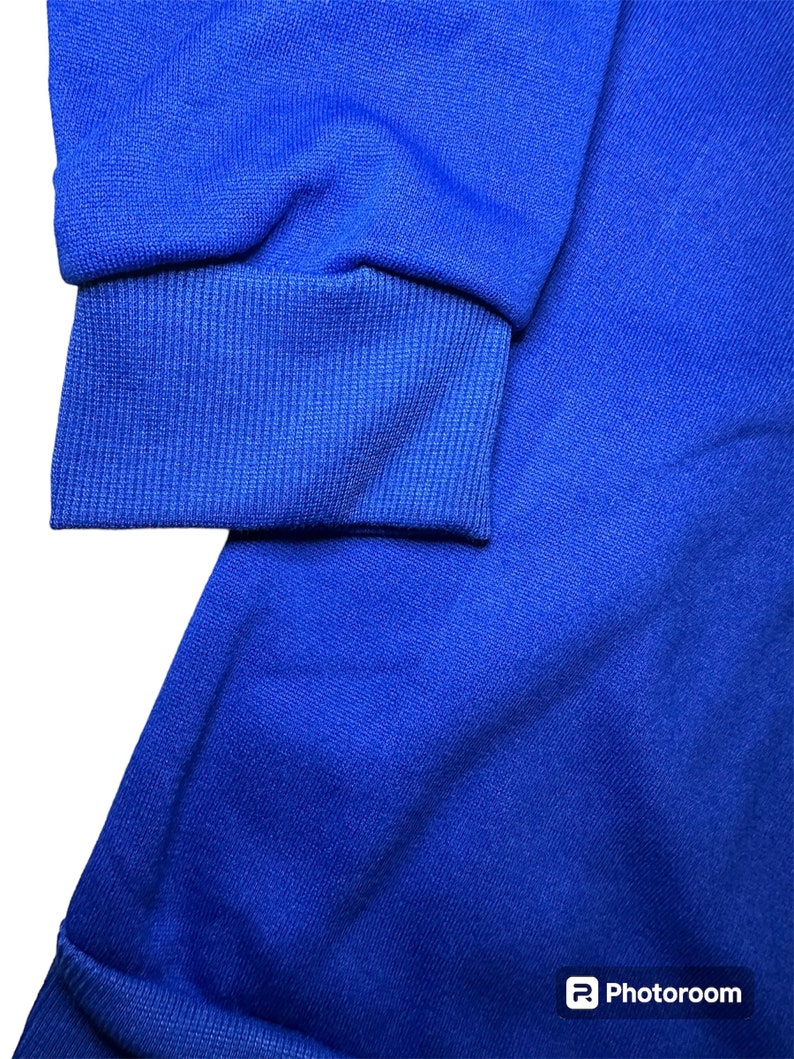 May include: A close-up of a royal blue sweatshirt with ribbed cuffs. The fabric is soft and textured.