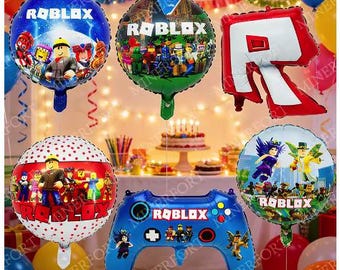 May include: A collection of six Roblox-themed foil balloons, including four round balloons with various character graphics, one large red letter R balloon, and one blue game controller-shaped balloon, all featuring the Roblox logo text.
