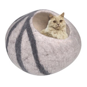 以下が含まれることがあります： グレーとブラックのフェルト製の猫用ベッド。ベッドは球形で、猫が出入りできる大きな開口部があります。ベッドには黒と白のストライプ模様があります。