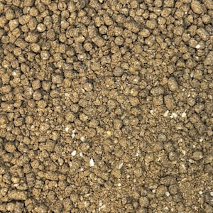 May include: Close-up of a pile of small, brown, granular pellets. The pellets are tightly packed together, with a slightly uneven texture. There are also small, lighter-colored particles mixed in, creating a speckled appearance. The overall color is a muted brown.