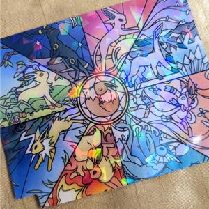 Könnte beinhalten: Holografische Karte mit einem Buntglas-Design, das verschiedene Pokémon zeigt. In der Mitte befindet sich ein Evoli, umgeben von seinen Entwicklungen, mit leuchtenden Farben und einem schimmernden Effekt. Das Design ist in verschiedene Abschnitte unterteilt.