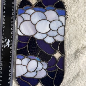 May include: A stained glass window hanging with a chain. The window is oval shaped and features a design of white and blue circles on a dark blue background.