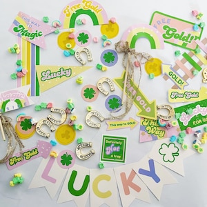 Könnte beinhalten: Eine Sammlung von Dekorationen für eine St. Patrick's Day Party, darunter grüne Kleeblätter, goldene Hufeisen-Anhänger und bunte Banner mit Sätzen wie "Free Gold", "Lucky" und "This Way to Magic".