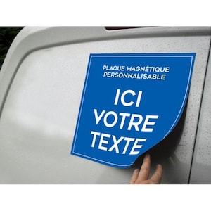 Peut inclure: Un panneau magnétique bleu avec du texte blanc indiquant "PLAQUE MAGNÉTIQUE PERSONNALISABLE" et "ICI VOTRE TEXTE". Le panneau est fixé sur une surface de véhicule blanche.