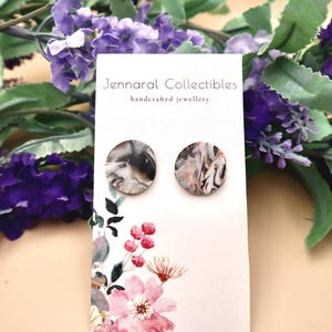 Könnte beinhalten: Ein Paar runde Ohrringe aus weißem und schwarzem Marmor auf einer weißen Karte mit dem Text "Jennaral Collectibles handcrafted jewellery".