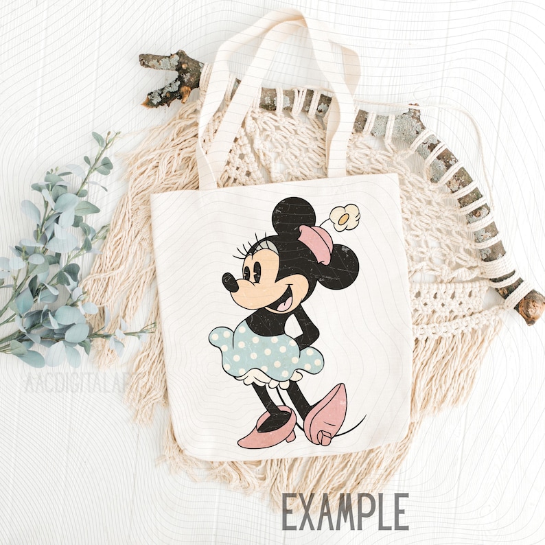 K&ouml;nnte beinhalten: Eine wei&szlig;e Tragetasche mit einer Vintage-Illustration von Minnie Mouse. Minnie tr&auml;gt ein blaues Polka-Dot-Kleid, rosa Schuhe und eine passende Schleife. Das Wort "EXAMPLE" ist unten auf der Tasche aufgedruckt.