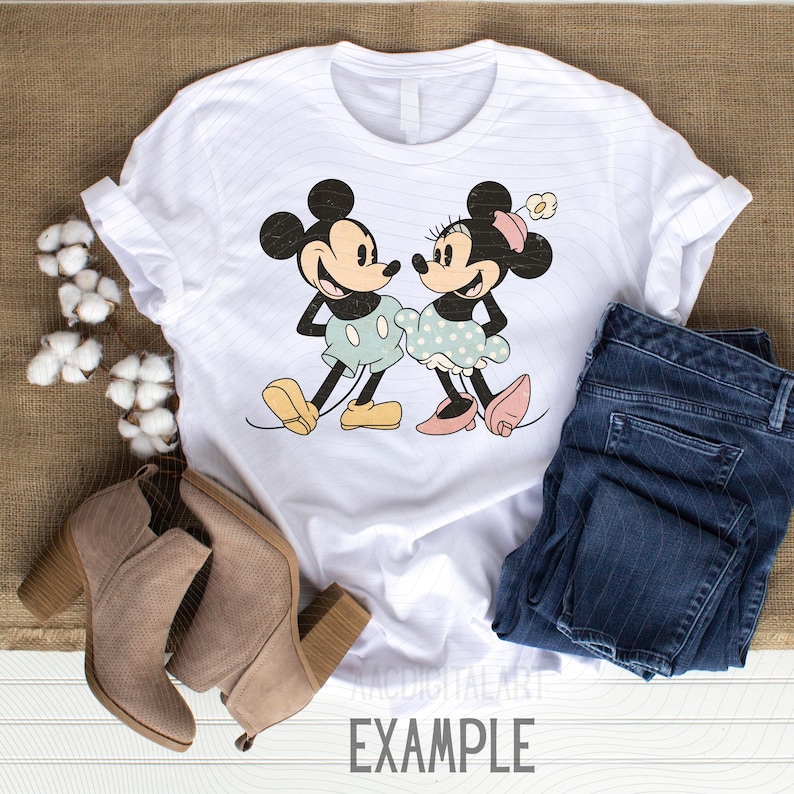 K&ouml;nnte beinhalten: Wei&szlig;es T-Shirt mit einer Cartoon-Illustration von Mickey und Minnie Mouse. Mickey tr&auml;gt hellblaue Shorts und gelbe Schuhe, Minnie ein gepunktetes Kleid und rosa Schuhe. Das Wort "EXAMPLE" ist unten aufgedruckt.
