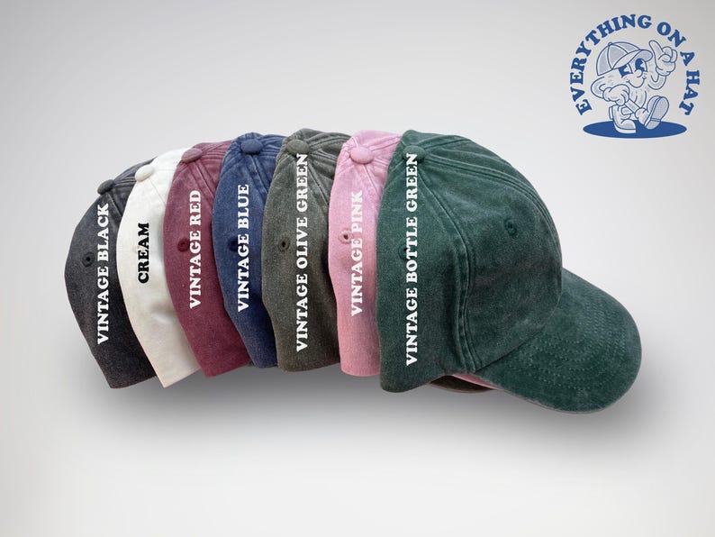 K&ouml;nnte beinhalten: Ein Set aus acht Baseballkappen in verschiedenen Farben, darunter Schwarz, Creme, Rot, Blau, Olivgr&uuml;n, Pink und Flaschengr&uuml;n. Jede Kappe hat eine andere Farbe und ein wei&szlig;es Textetikett, das die Farbe angibt.
