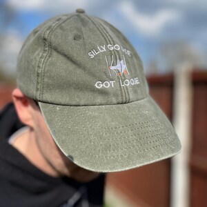 May include: A green baseball cap with the text "Silly Goose Got Loose" embroidered on the front. The text is in white with a small orange detail.