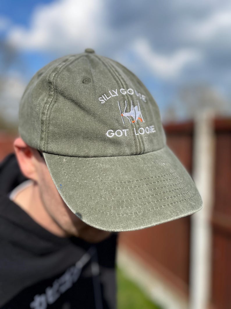 May include: A green baseball cap with the text "Silly Goose Got Loose" embroidered on the front. The text is in white with a small orange detail.