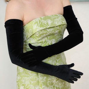 May include: A woman wearing a strapless green dress with a white floral pattern and long black velvet gloves.