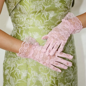 May include: A strapless green dress with a white floral pattern and a pair of pink lace gloves.
