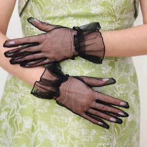 May include: A pair of black sheer gloves with ruffled edges. The gloves are made of a delicate, lightweight fabric and have a classic, elegant design.