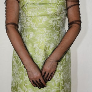 May include: A woman wearing a strapless green dress with a white floral pattern and black sheer gloves.