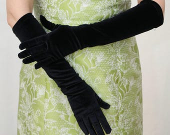 May include: A woman wearing a green floral dress and long black velvet gloves.