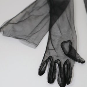 May include: A pair of black sheer long gloves with a delicate mesh pattern. The gloves are made of a soft, lightweight fabric and have a fitted design.