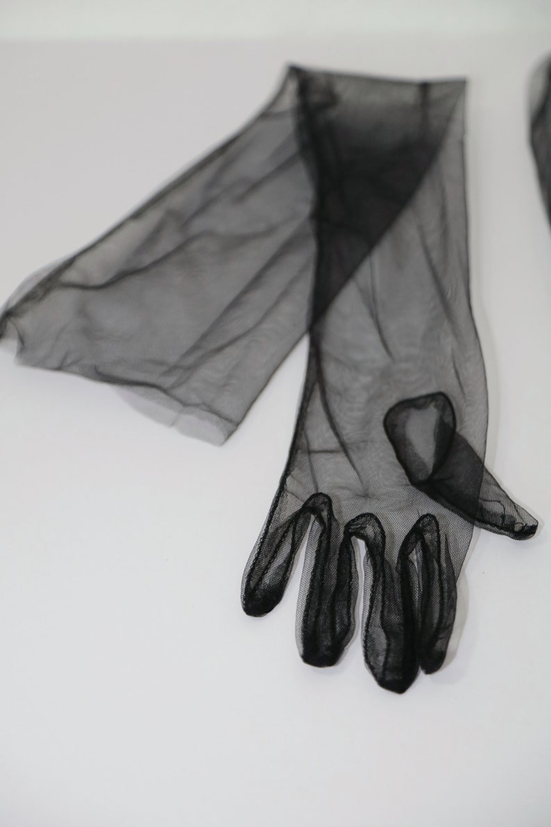 May include: A pair of black sheer long gloves with a delicate mesh pattern. The gloves are made of a soft, lightweight fabric and have a fitted design.