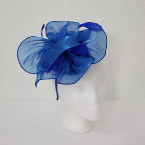 May include: A blue headband with a large, layered flower made of tulle and feathers.