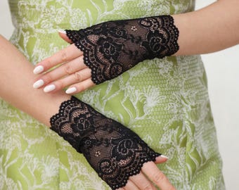 May include: A pair of black lace fingerless gloves with a scalloped edge. The gloves are made of delicate lace and are perfect for adding a touch of elegance to any outfit.