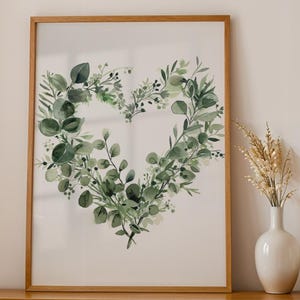 May include: A framed watercolor print of a heart shape made of green leaves and branches. The print is on a white background and has a wooden frame.