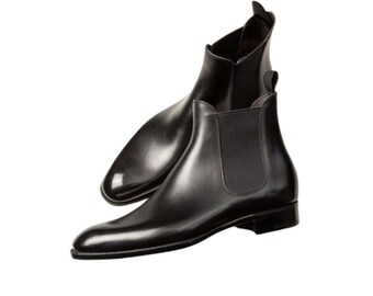 May include: A pair of black leather Chelsea boots featuring a smooth, polished finish, rounded toes, and elastic side panels. Each boot includes a small pull tab at the top of the heel collar and a low, stacked heel with a slim, dark outsole.