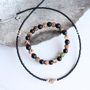 May include: A black beaded necklace and a bracelet with black and brown agate beads. The bracelet has a silver clasp.