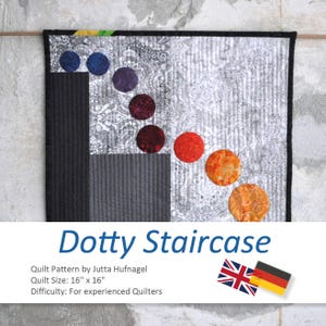 Könnte beinhalten: Eine gesteppte Wandbehänge mit schwarzem Rand und dem Text "Dotty Staircase". Der Quilt zeigt ein Design aus bunten Kreisen auf einem silbernen und grauen Hintergrund. Der Quilt misst 40,6 cm x 40,6 cm.