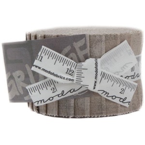 May include: A roll of beige fabric strips, tied with a white ribbon printed with ruler markings and the text "moda fabrics". A gray tag with the word "GRUNGE" is attached to the roll.