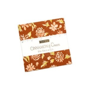 May include: A stack of fabric squares with a floral pattern in shades of brown, peach, and green. The fabric is wrapped with a white band that reads "Cinnamon & Cream" and "Fig Tree & Co."