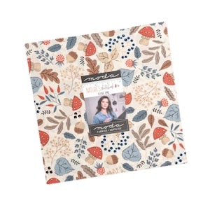 May include: A square fabric bundle with a cream background, featuring a repeating pattern of red mushrooms, blue berries, and brown leaves. The fabric bundle includes a label with the text "Nature's Sketchbook" and a photo of a woman.