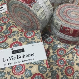 May include: Fabric bundles and rolls with floral patterns in red, blue, and beige. The fabric is labelled "La Vie Bohème by French General." Rolls are wrapped with measuring tape. Suitable for quilting and sewing projects.