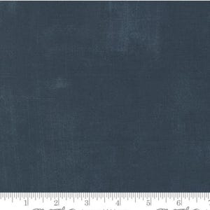 May include: Close-up of dark blue fabric with a textured surface. The material has a distressed appearance with tonal variations. The fabric is suitable for quilting or other craft projects. The fabric is measured in inches.