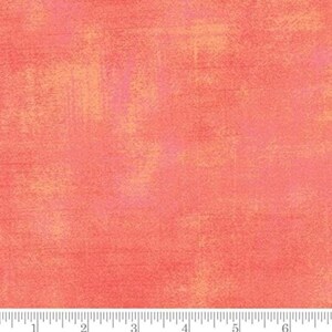 May include: Textured fabric with a watercolour effect. The fabric features a blend of coral, peach, and pink hues, creating a warm aesthetic. The design has a mottled appearance, with subtle variations in colour.