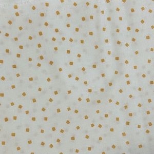 May include: Cream-coloured fabric featuring a repeating pattern of small, ochre-yellow squares. The squares are evenly distributed across the surface, creating a simple, yet visually appealing design. The fabric appears to be cotton or a similar lightweight material.