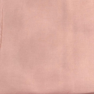 May include: A piece of pale pink fabric with a textured surface. The fabric is a solid colour, with a slightly irregular appearance. The edges of the fabric are visible on the left side.