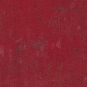 May include: A deep red fabric with a distressed texture. The surface shows subtle colour variations and imperfections, giving a vintage or worn look. The fabric appears to be a cotton or linen blend, suitable for various craft projects.