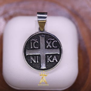 以下が含まれることがあります： 黒い十字架と「IC XC NI KA」の刻印が円形に施されたシルバーペンダント